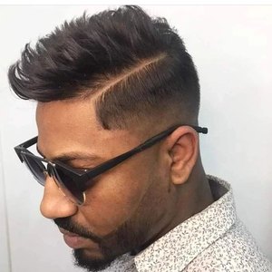 Homem de óculos escuros de perfil, com undercut desconectado e barba aparada.